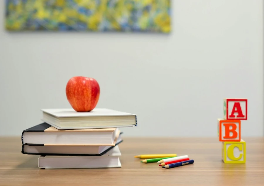 Libros, una manzana y materiales escolares, fotografía ilustrativa de educación